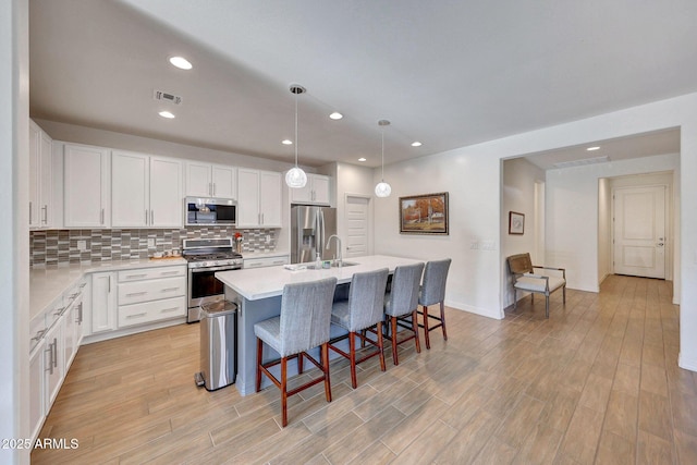 kitchen with a kitchen bar, decorative backsplash, white cabinets, and stainless steel appliances
