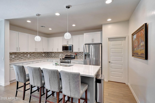 kitchen featuring light countertops, a kitchen breakfast bar, light wood-type flooring, and stainless steel appliances