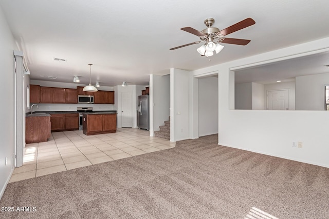 unfurnished living room with sink, light carpet, and ceiling fan