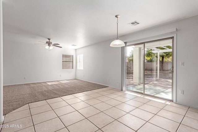 spare room with a wealth of natural light, light colored carpet, and ceiling fan