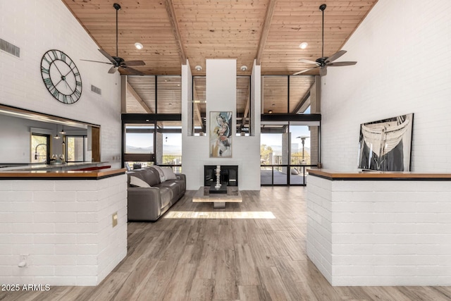 living area featuring a high ceiling, a ceiling fan, and wood ceiling