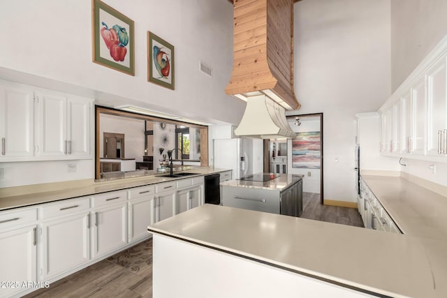 kitchen with visible vents, a high ceiling, a center island, and a sink
