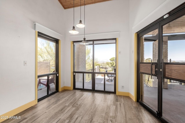 doorway with wood finished floors, french doors, a high ceiling, and baseboards