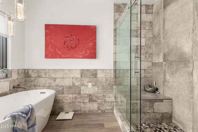 full bathroom featuring tile walls, a freestanding tub, a stall shower, and wood finished floors