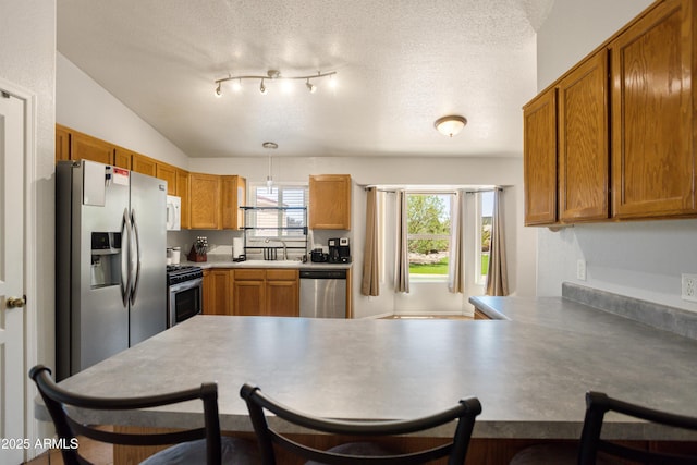 3501 Camino Bella Rosa, Sierra Vista, AZ 85650 - kitchen with a kitchen breakfast bar, a textured ceiling, a sink, a peninsula, and stainless steel appliances