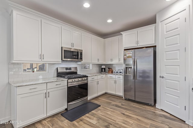 19415 W College Dr, Litchfield Park, AZ 85340 - kitchen with stainless steel appliances, white cabinetry, tasteful backsplash, recessed lighting, and light wood-type flooring