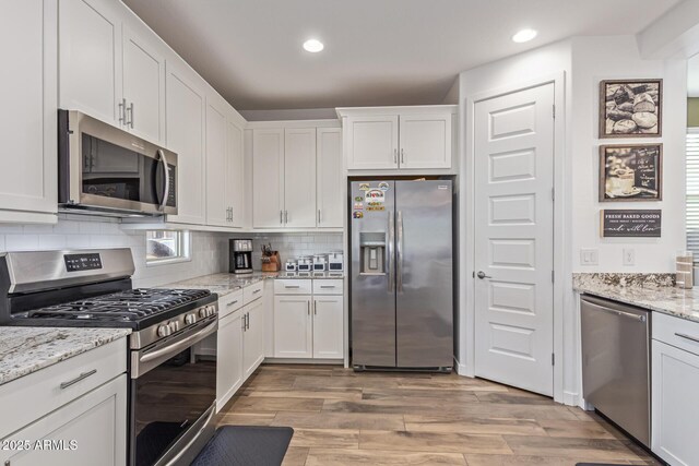 19415 W College Dr, Litchfield Park, AZ 85340 - kitchen featuring appliances with stainless steel finishes, white cabinetry, light wood-style flooring, recessed lighting, and tasteful backsplash