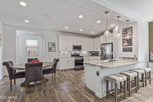 19415 W College Dr, Litchfield Park, AZ 85340 - kitchen with appliances with stainless steel finishes, a peninsula, wood finished floors, white cabinets, and a breakfast bar area