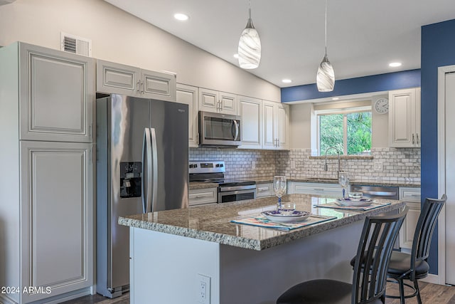 kitchen featuring decorative backsplash, a center island, dark wood-type flooring, sink, and appliances with stainless steel finishes