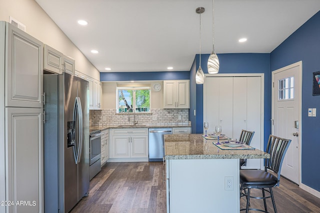 kitchen featuring tasteful backsplash, a center island, a sink, a kitchen bar, and stainless steel appliances