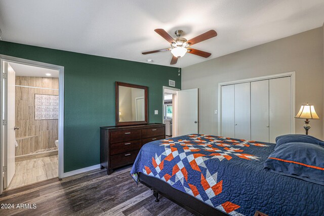 bedroom featuring a closet, baseboards, dark wood finished floors, ensuite bath, and ceiling fan