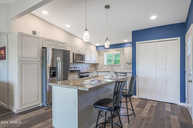 kitchen with lofted ceiling, tasteful backsplash, a kitchen island, dark wood-type flooring, and appliances with stainless steel finishes