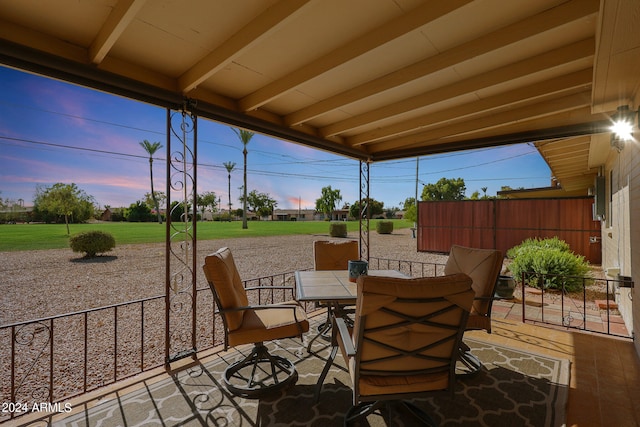 patio terrace at dusk featuring a lawn