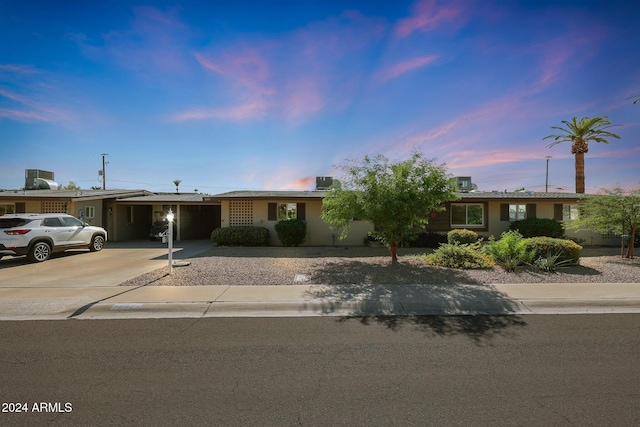 ranch-style home with central AC unit, an attached carport, and concrete driveway
