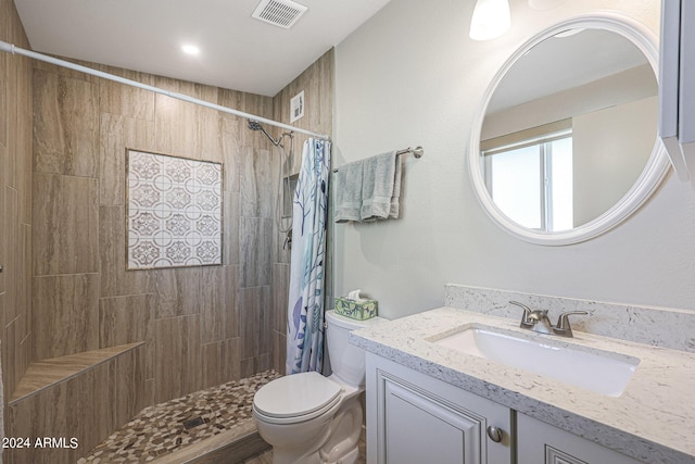full bath with tiled shower, vanity, visible vents, and toilet