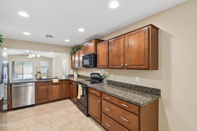 kitchen with visible vents, brown cabinetry, a sink, dark stone counters, and black appliances