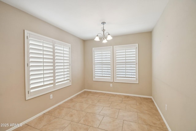 empty room with baseboards and a chandelier