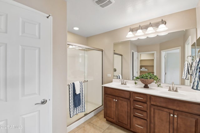 bathroom featuring double vanity, a stall shower, visible vents, tile patterned flooring, and a sink