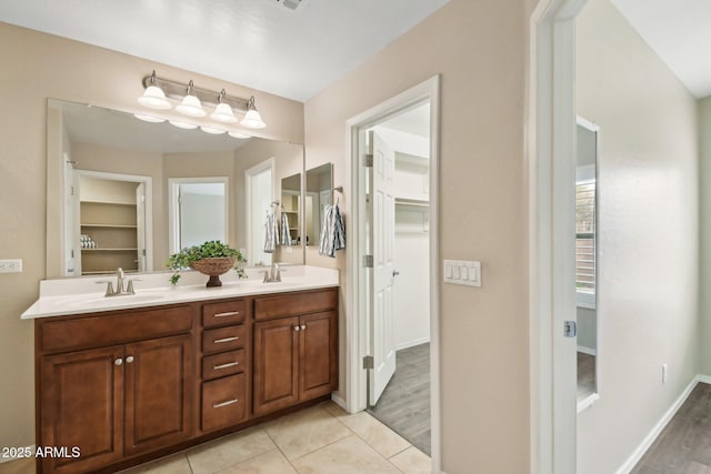 bathroom with double vanity, a spacious closet, a sink, and tile patterned floors