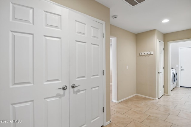 hall featuring visible vents, washer and clothes dryer, baseboards, and light tile patterned floors