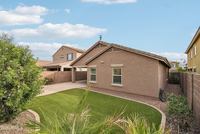 back of property with stucco siding, a patio, a fenced backyard, and a lawn