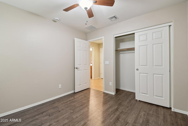 unfurnished bedroom with baseboards, visible vents, dark wood finished floors, and a closet