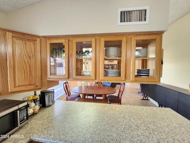 dining space featuring light tile patterned flooring, vaulted ceiling, and a textured ceiling