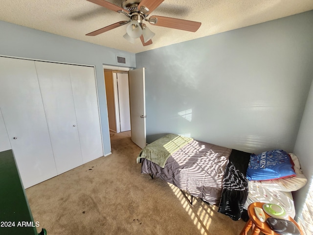 carpeted bedroom featuring a closet, a textured ceiling, and ceiling fan