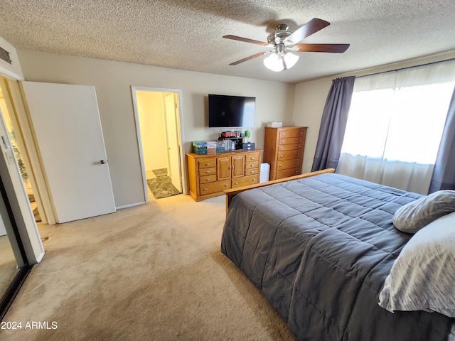 carpeted bedroom with ceiling fan, connected bathroom, and a textured ceiling