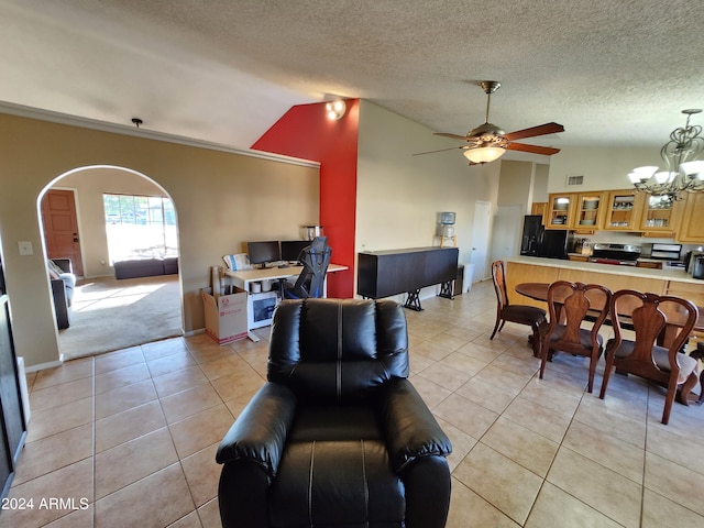 living room featuring ceiling fan with notable chandelier, lofted ceiling, light tile patterned floors, and a textured ceiling