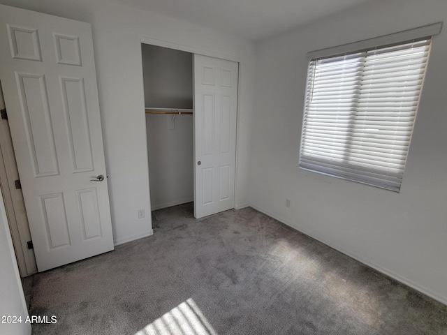 unfurnished bedroom with light colored carpet and a closet