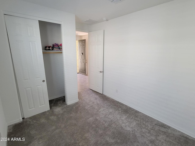 unfurnished bedroom with dark carpet and a closet