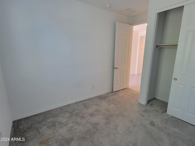 unfurnished bedroom with light carpet and a closet