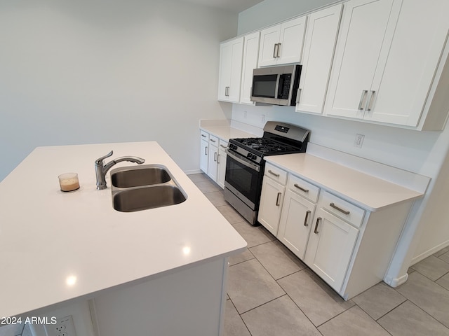 kitchen with white cabinets, stainless steel appliances, a center island with sink, and sink