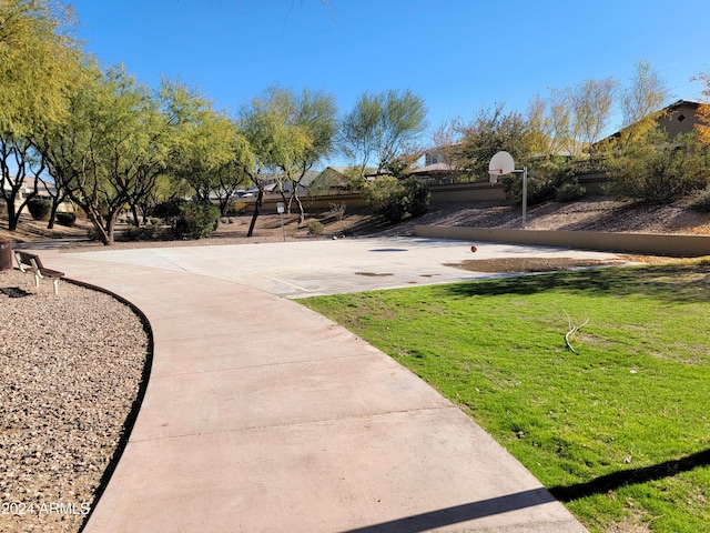 view of home's community with basketball hoop and a yard