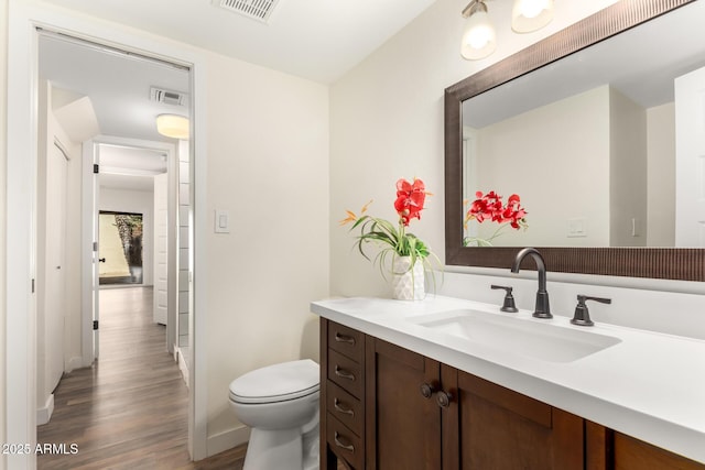 bathroom featuring vanity, wood-type flooring, and toilet