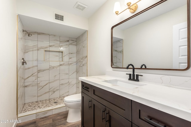 bathroom with vanity, toilet, and tiled shower