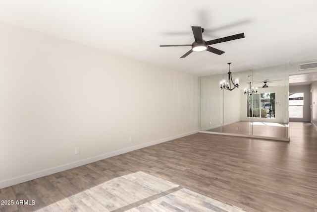 spare room with hardwood / wood-style flooring and ceiling fan with notable chandelier