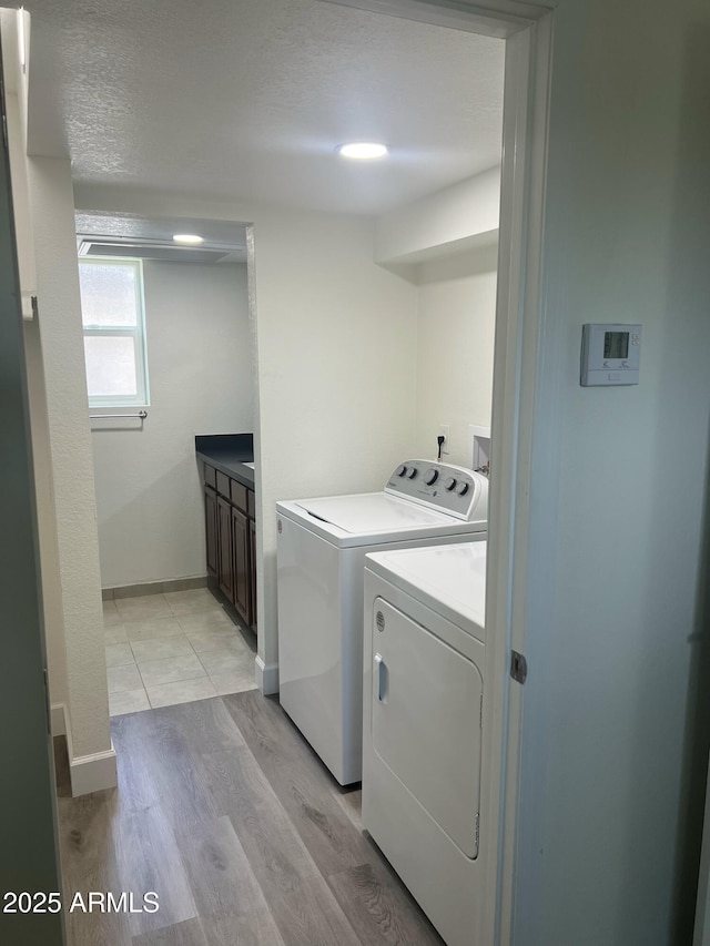 clothes washing area with separate washer and dryer, a textured ceiling, and light hardwood / wood-style flooring