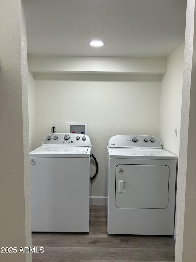 laundry room with washing machine and clothes dryer and dark hardwood / wood-style flooring