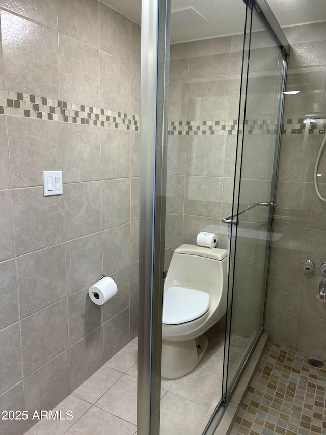 bathroom featuring tile patterned floors, toilet, and walk in shower