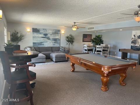 game room featuring a textured ceiling, carpet floors, ceiling fan, and pool table