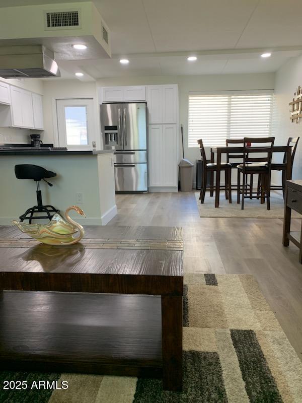 interior space featuring white cabinetry, stainless steel fridge, plenty of natural light, and light hardwood / wood-style flooring