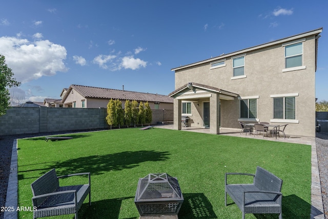 back of house with a lawn, a patio area, and a fire pit