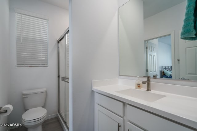 bathroom featuring vanity, toilet, and a shower with door