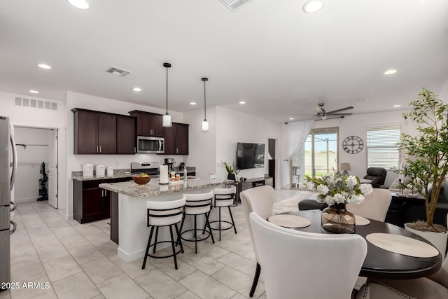 3670 E Sandoval Dr, San Tan Valley, AZ 85140 - kitchen with a breakfast bar, dark brown cabinets, a ceiling fan, appliances with stainless steel finishes, and open floor plan