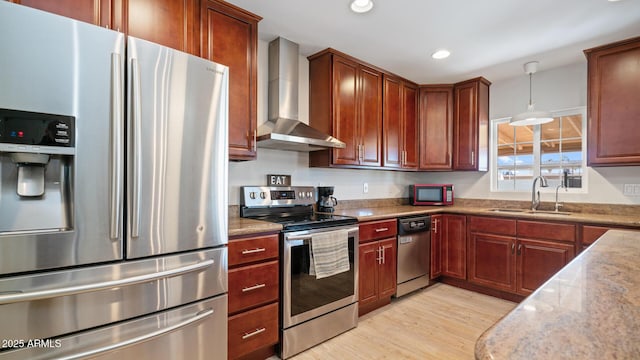 kitchen with wall chimney exhaust hood, sink, hanging light fixtures, light hardwood / wood-style flooring, and stainless steel appliances