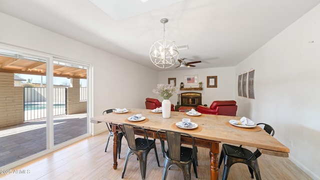 dining space with ceiling fan with notable chandelier and light hardwood / wood-style flooring