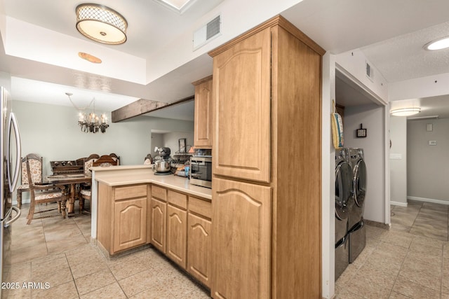 kitchen featuring separate washer and dryer, light brown cabinets, a chandelier, and kitchen peninsula