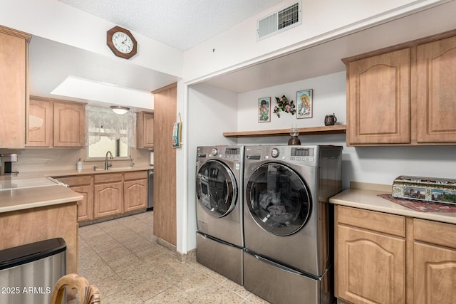 laundry area with separate washer and dryer, sink, and a textured ceiling